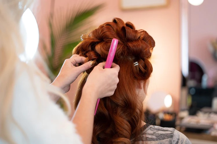 A salon stylist fixing a woman’s hairA salon stylist fixing a woman’s hair