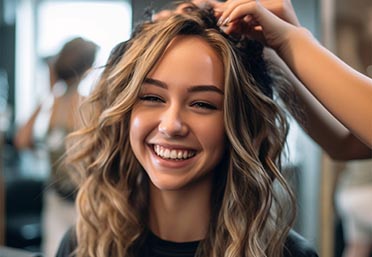 A woman smiles while getting services at our hair extension salon